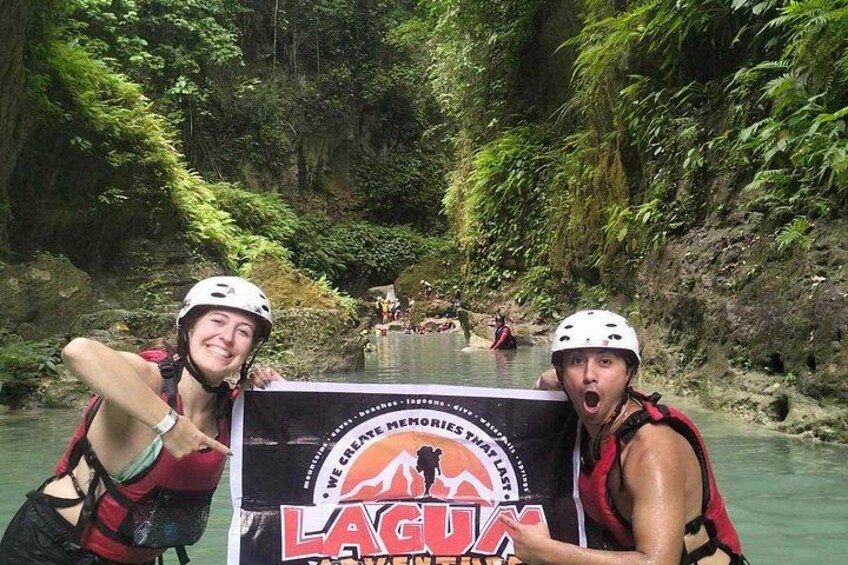 Two people in a river with a banner that reads 'LAGUNA'. 5