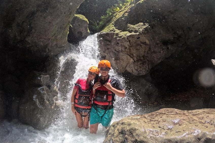 Two people in a water stream surrounded by rocky terrain. 2