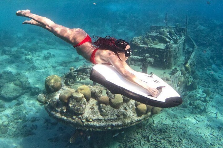 A person swimming underwater with a surfboard. 1