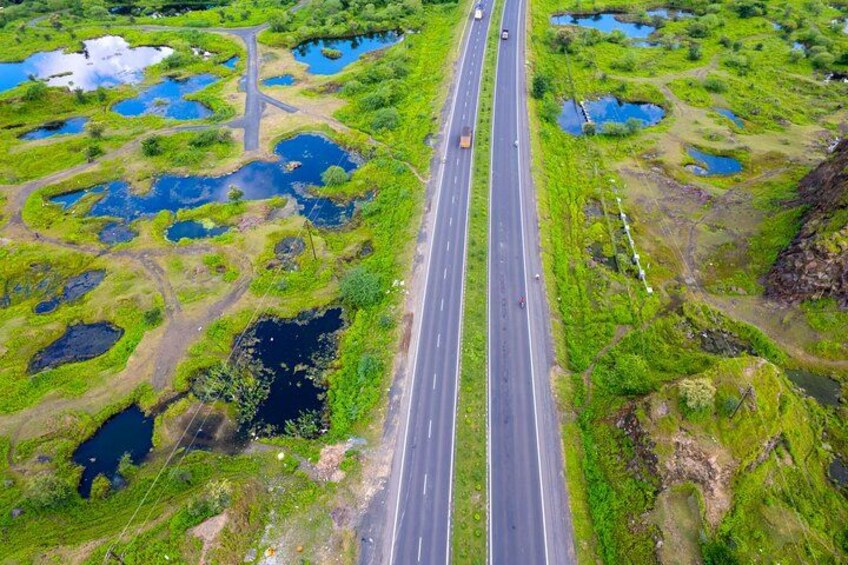 A highway cutting through a wetland area with multiple ponds and green vegetation. 2