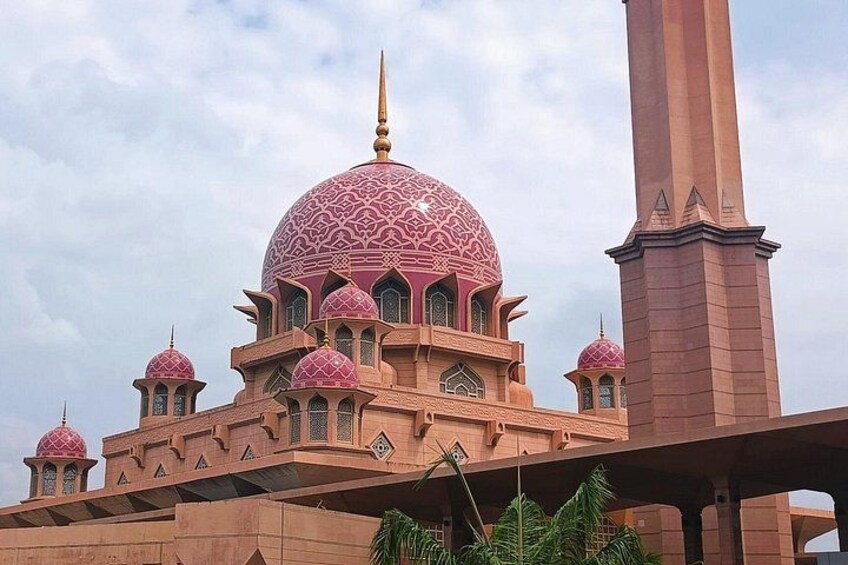 A mosque with a large central dome and smaller domes, a tall minaret, and a minaret with a pointed top. 1