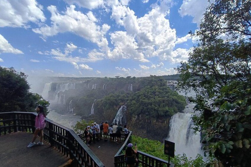 Une cascade comportant plusieurs chutes d’eau, une plateforme d’observation où se trouvent des personnes, et une végétation luxuriante. 2