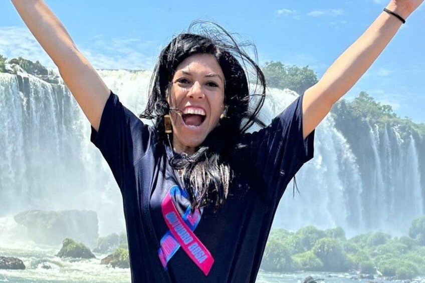 Une personne, les bras levés, se tient devant une cascade. 3