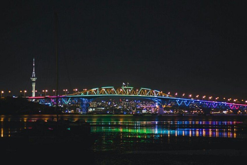 Un puente iluminado con luces de colores que se reflejan en el agua. 1