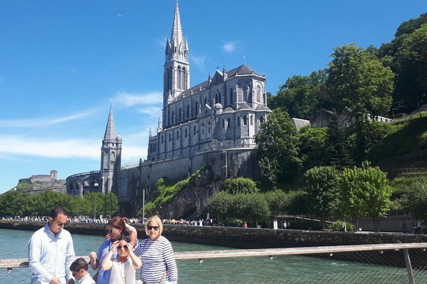 Una catedral con una aguja alta, un cuerpo de agua y un grupo de personas en la orilla. 5