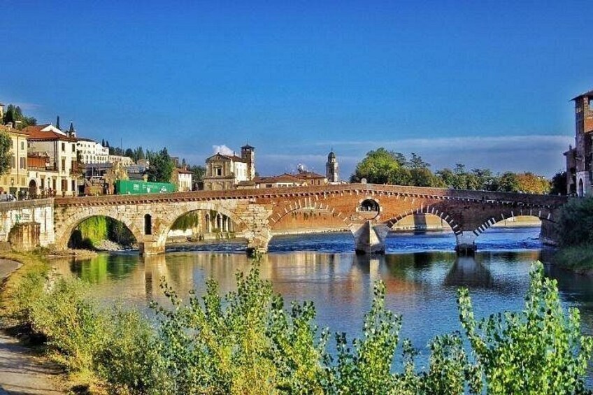 Un pont de pierre enjambant une rivière, avec des bâtiments et de la végétation tout autour. 1