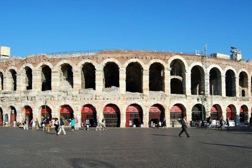 An ancient Roman amphitheater with multiple arches and a crowd of people. 2