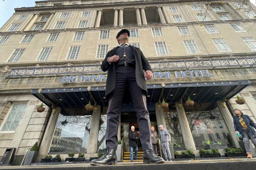 Un hombre frente al Hotel Britannia, vestido con traje y sombrero. 2