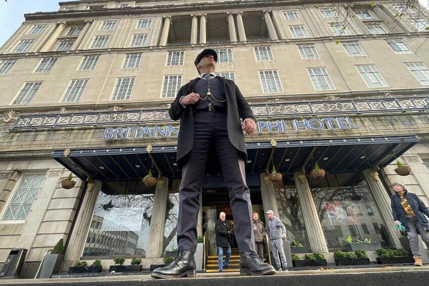 A man in a suit standing in front of the Britannia Hotel. 4
