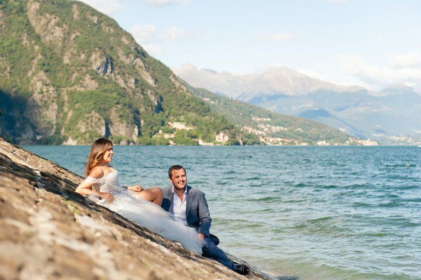 A couple sitting by a lakeside with mountains in the background. 4