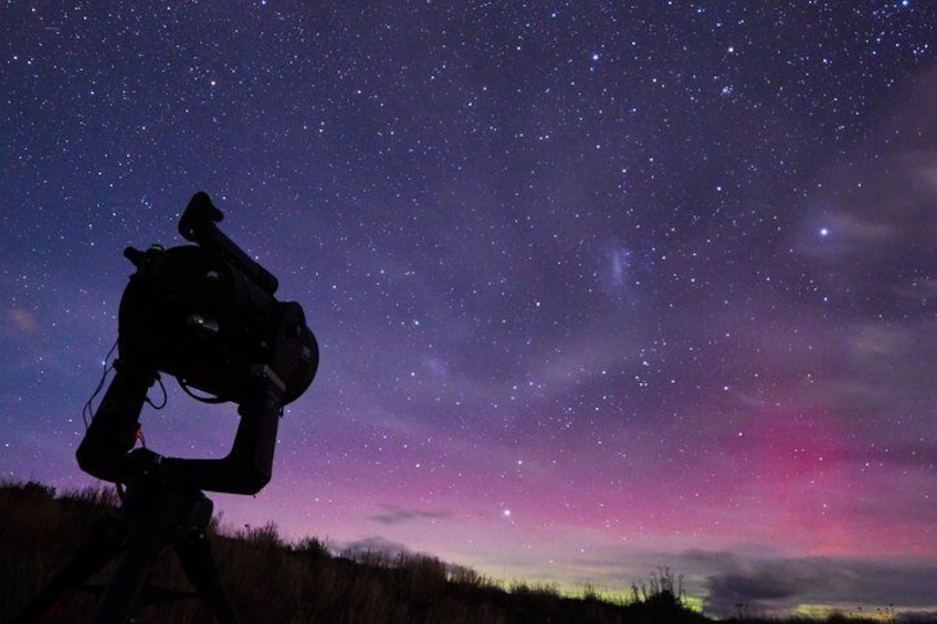 A person with a camera on a tripod under a starry night sky. 1