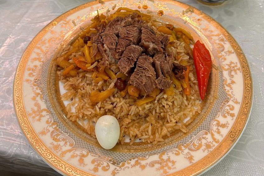 A plate of biryani with meat, rice, and vegetables. 2