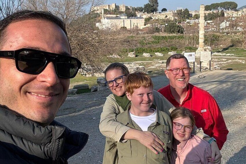 A group of people in a historical site with ruins and a tall monument in the background. 1