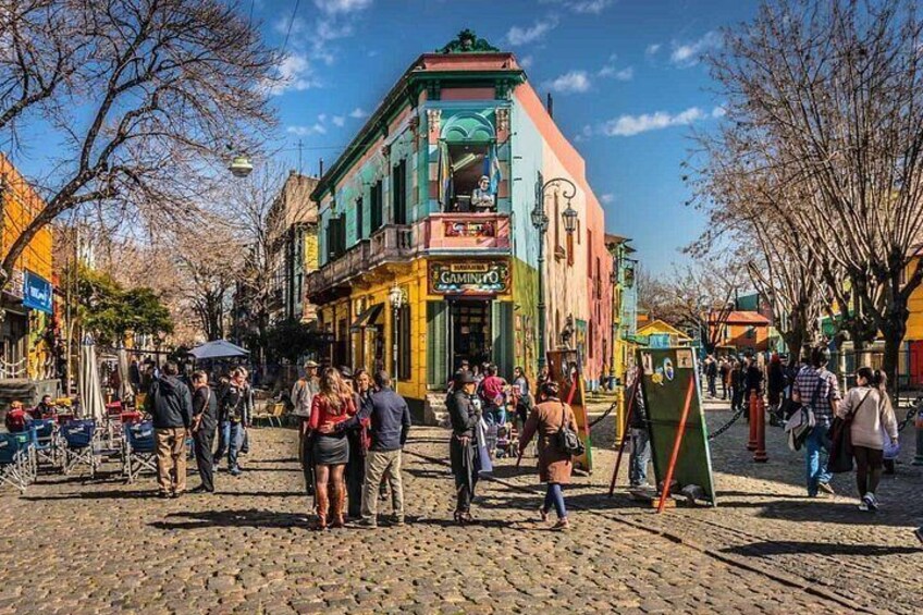 Una strada acciottolata fiancheggiata da edifici colorati e persone che passeggiano. 1