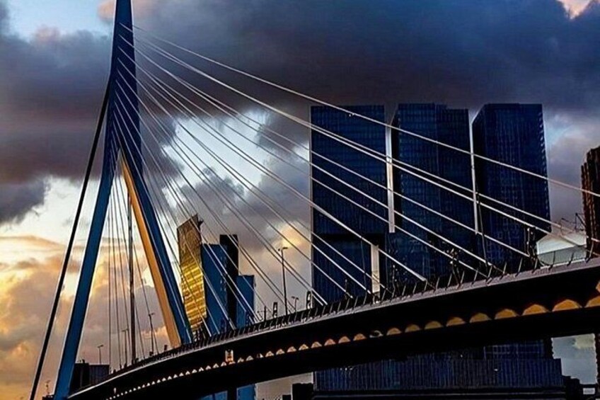 A cable-stayed bridge with a modern design, a city skyline with high-rise buildings, and a dramatic sky with clouds. 5