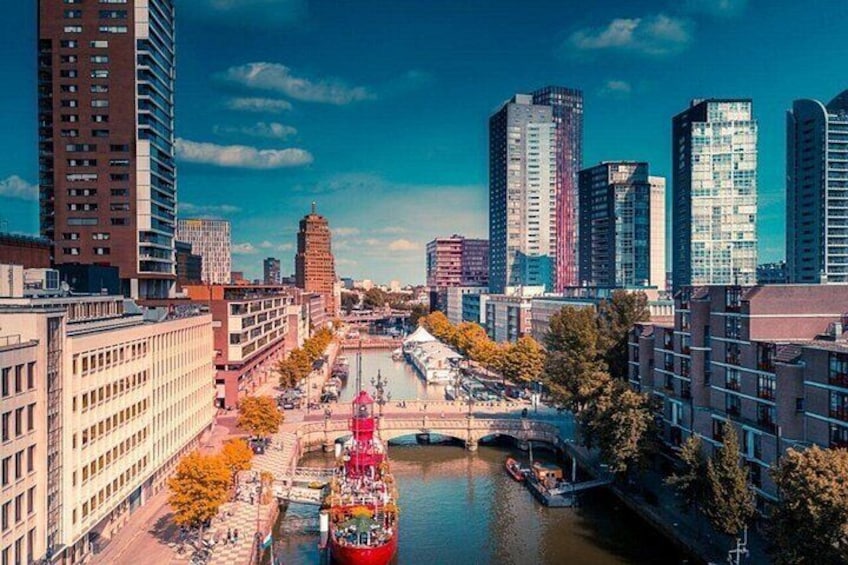 A river with a red boat, a bridge, and modern buildings along the riverbanks. 2