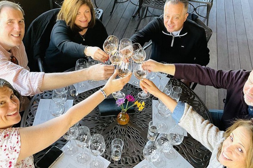 A group of people toasting with wine glasses around a table. 1