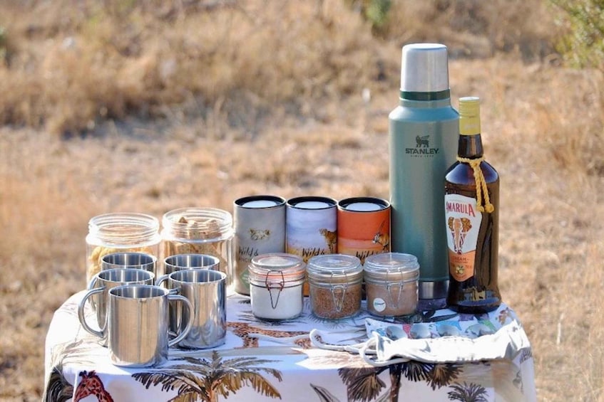 A collection of metal containers and a bottle on a table with a tropical print tablecloth. 3