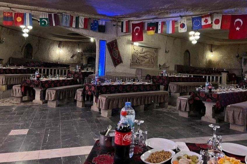 Un restaurante con varias mesas dispuestas para comer, banderas colgadas en las paredes y una lámpara azul. 5