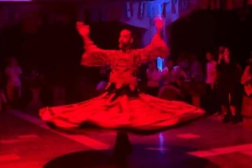 Una persona con un vestido rojo baila en un escenario, con un público de fondo. 3
