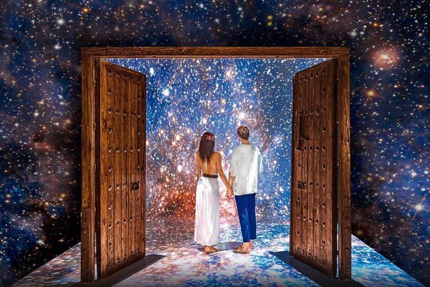 Una pareja de pie frente a una puerta de madera con un fondo espacial lleno de estrellas. 4