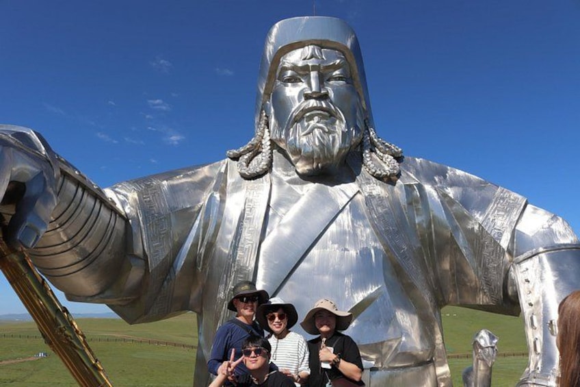 A large metallic statue of a historical figure with a raised arm, set against a clear blue sky. 1