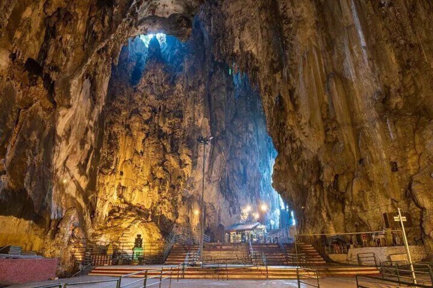 Una cueva con una abertura amplia, iluminada por luces artificiales, y una escalera que conduce al interior. 5