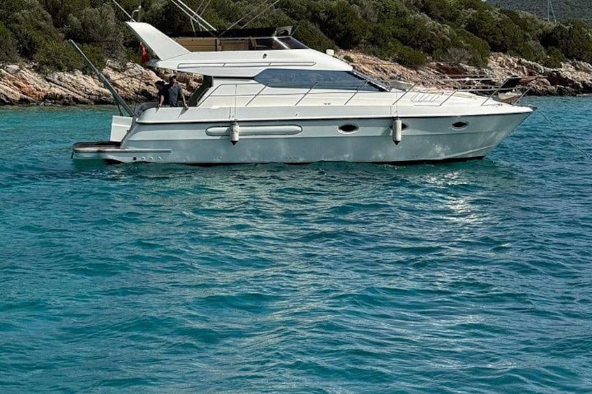 A white motorboat on calm water with a rocky shoreline in the background. 3