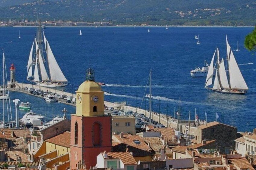 A coastal town with a prominent yellow tower, sailboats, and a lighthouse. 1