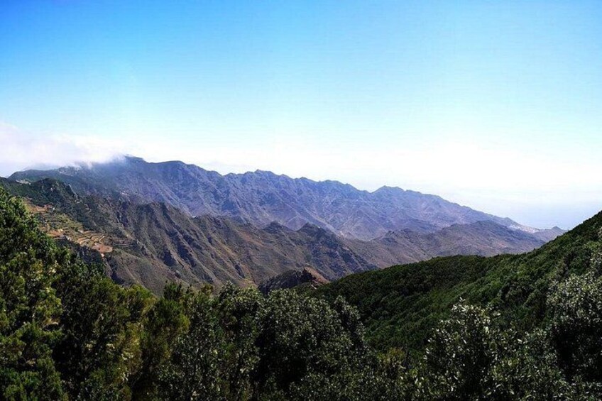 Un paisaje montañoso con vegetación verde intensa y cielo despejado. 1