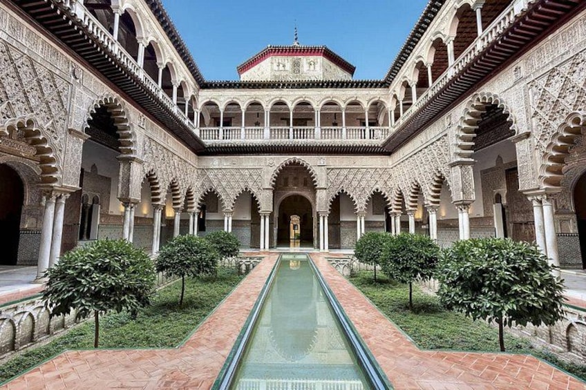 A courtyard with a central water channel, arches, and a tiled roof. 2