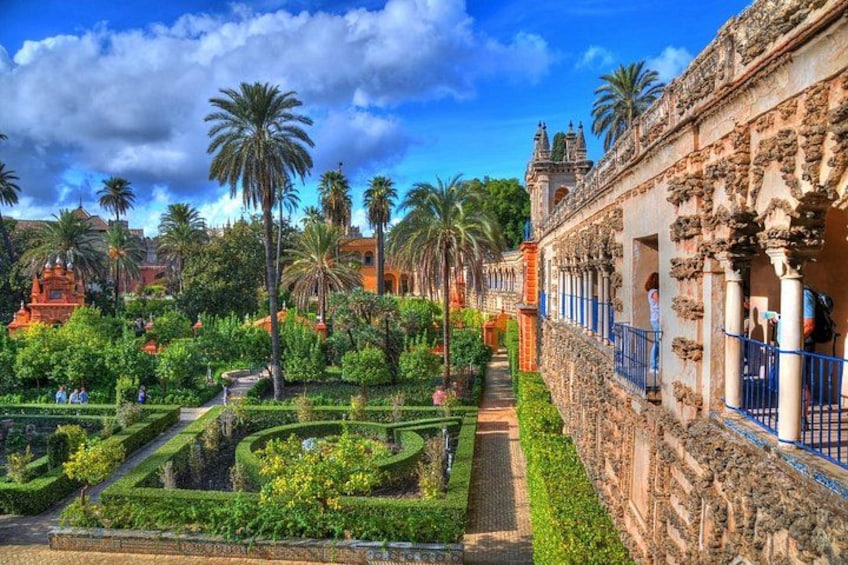 A garden with palm trees, a pathway, and a building with columns. 1