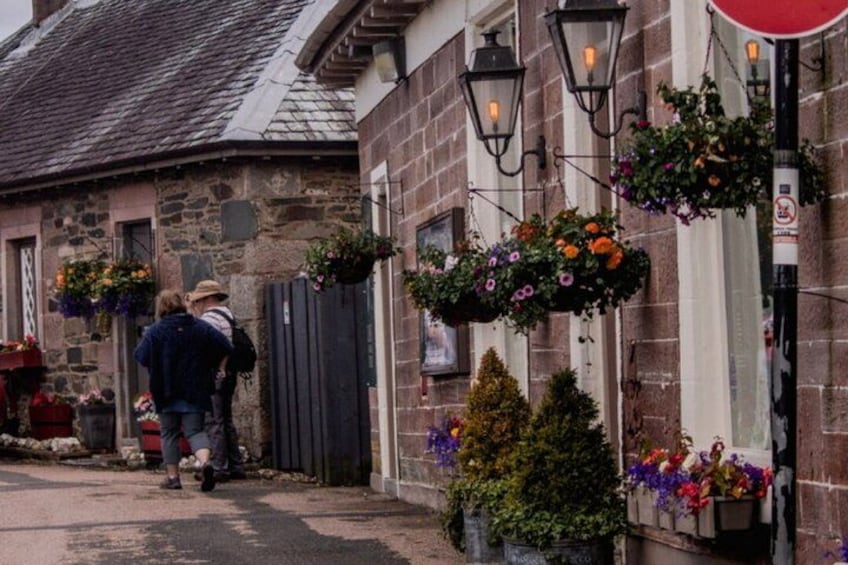 A stone building with hanging flower baskets and a red sign. 4