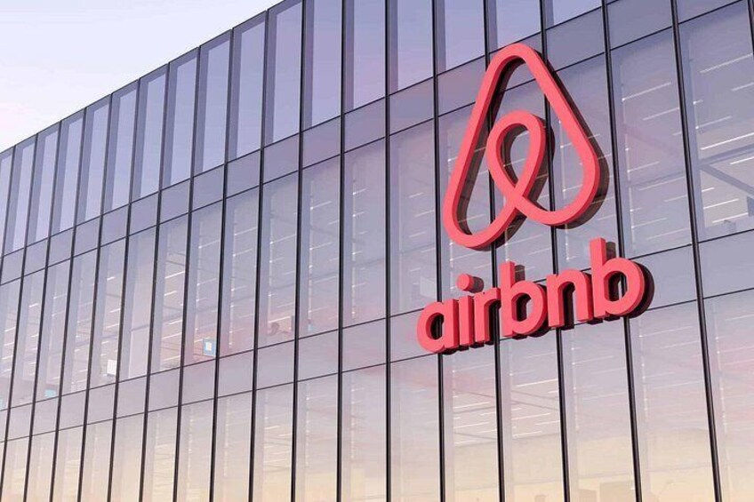 Een modern gebouw met een glazen gevel en het Airbnb logo. 2