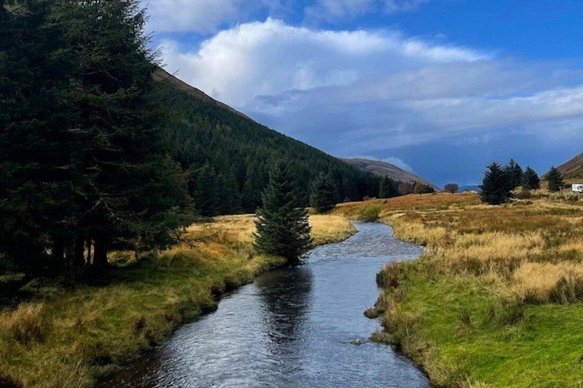 A river flowing through a forested valley with mountains in the background. 2