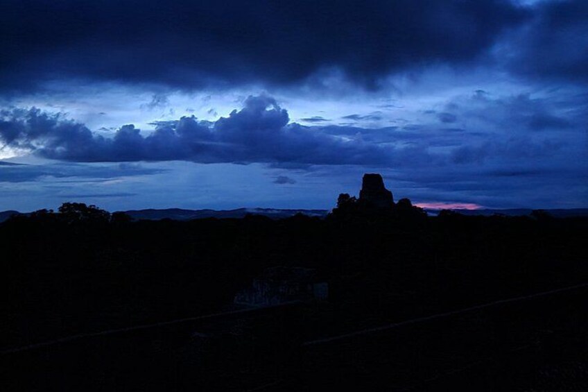 A rugged landscape with a prominent rock formation silhouetted against a twilight sky. 4
