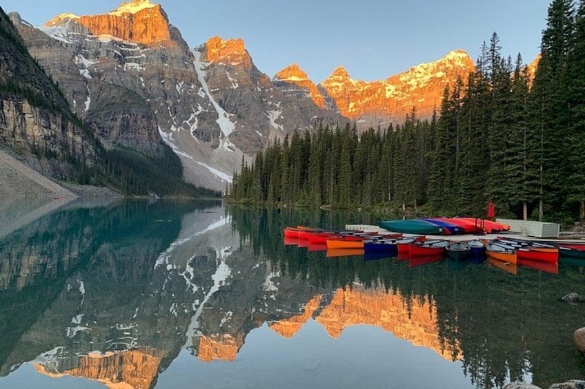 A calm lake with reflections of mountains and kayaks. 1