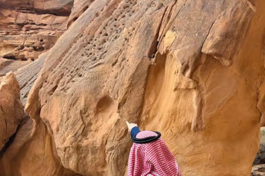A person in traditional attire climbing a large rock formation. 1