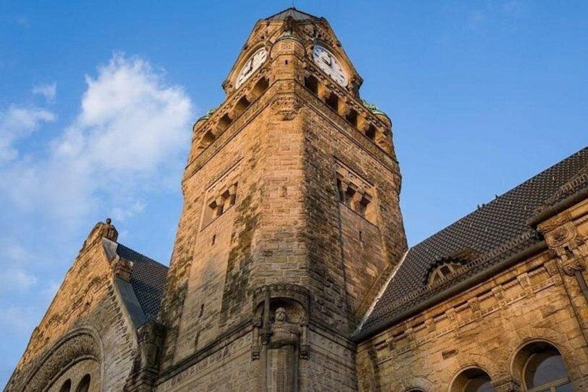 A historic stone building with a clock tower, arched windows, and a pointed roof. 2