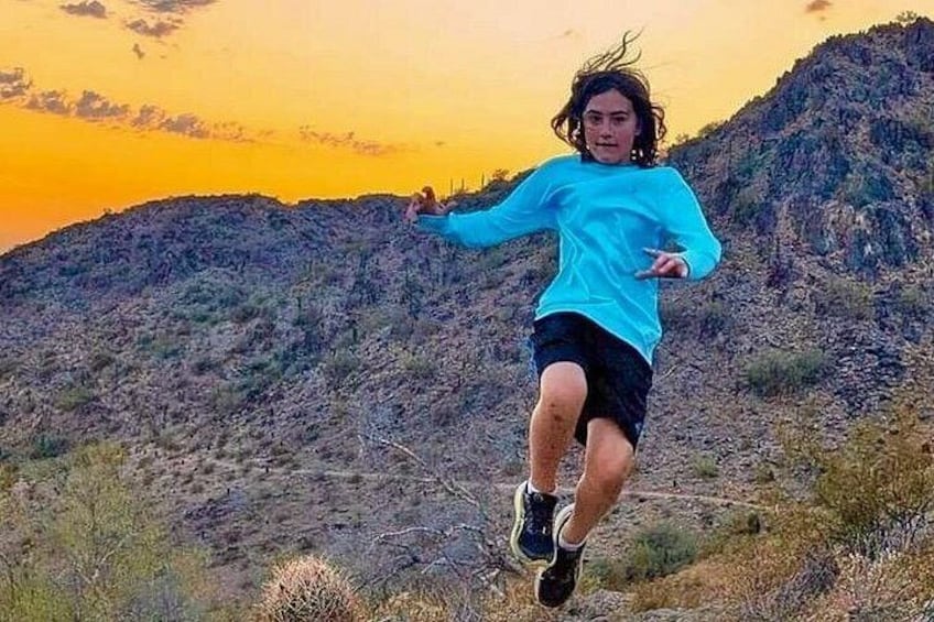 A person running on a mountain trail with a sunset in the background. 2