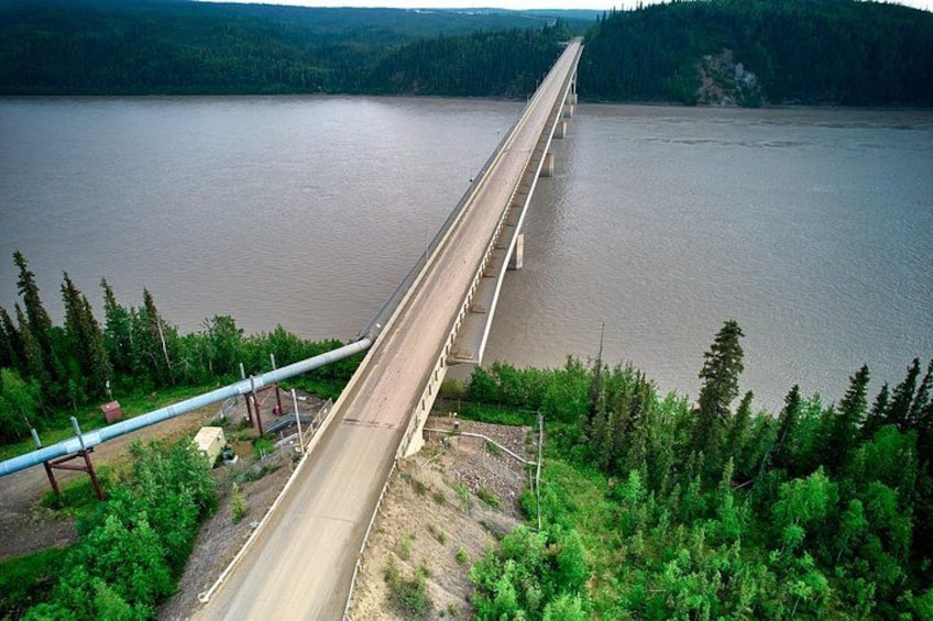 Un puente largo sobre un río tranquilo, rodeado de un bosque denso. 3