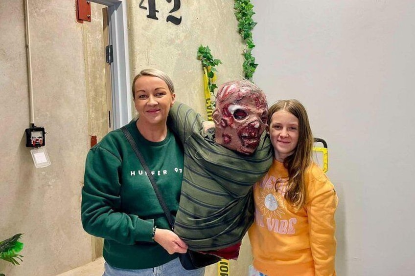 A hallway with a door marked '42' and a person in a green sweatshirt holding a child in a yellow sweatshirt. 2