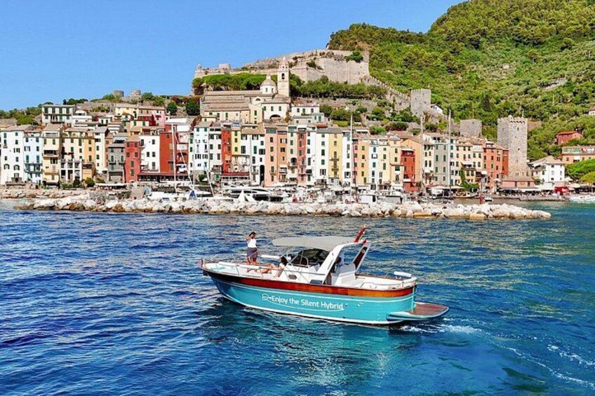 A boat named 'Greenjoy the Silent Hybrid' on a calm sea with a coastal town in the background. 2