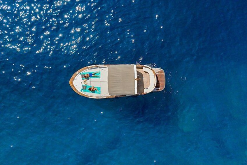 A boat with a deck and seating area on a calm blue sea. 1