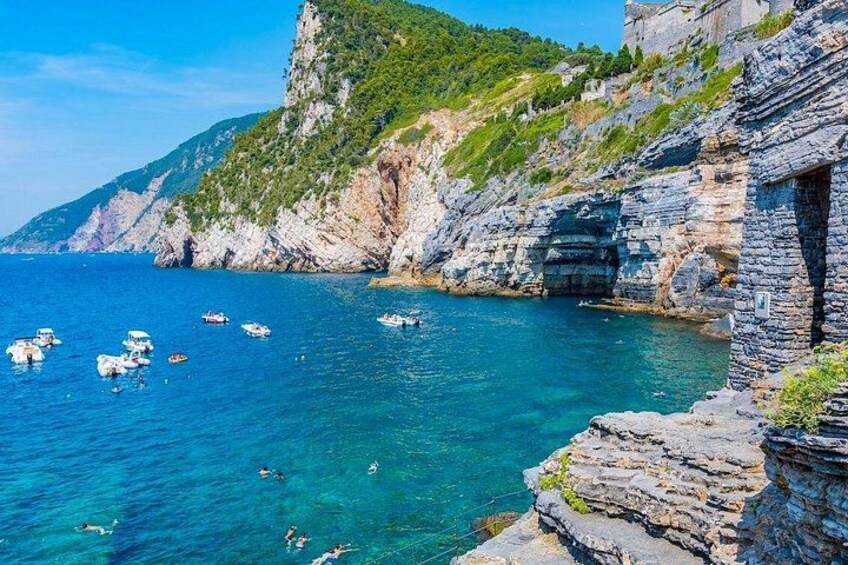 A coastal scene with clear blue water, rocky cliffs, and boats. 3