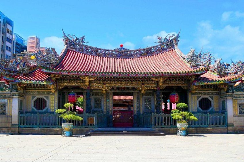 Een traditionele Chinese tempel met versierde architectuur, een rood dak en een grote centrale ingang. 2