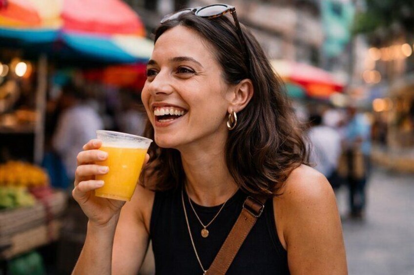 A person holding a glass of orange juice at an outdoor market. 2