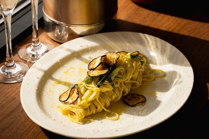 En tallerken spaghetti med grillede svampe og et glas vin på et træbord. 2