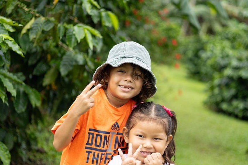 Twee kinderen in een open omgeving, met planten en begroeiing op de achtergrond. 5