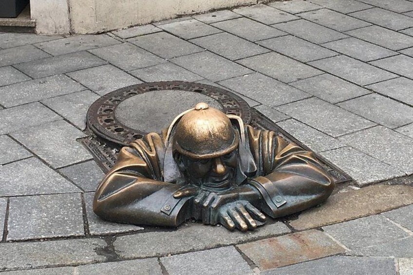 Eine bronzene Statue eines liegenden Mannes, dessen Kopf auf seinen Händen ruht. 5